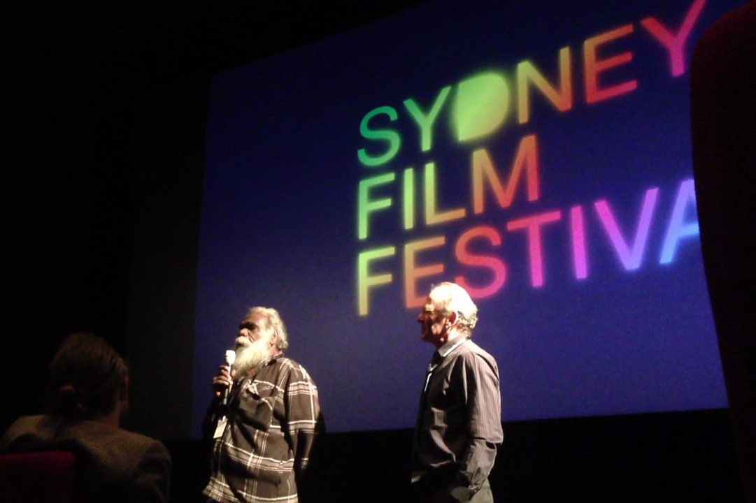 Low-angle shot of Mark speaking to audience at the Sydney Film Festival. Neil stands to the right.