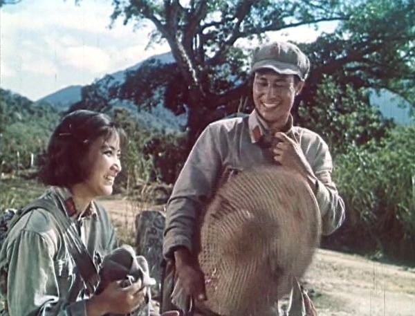 Two young solidiers in uniform walking along a dirt path laughing.