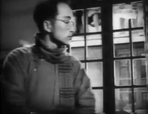 Bespectacled man in coat and scarf nearer the camera.
