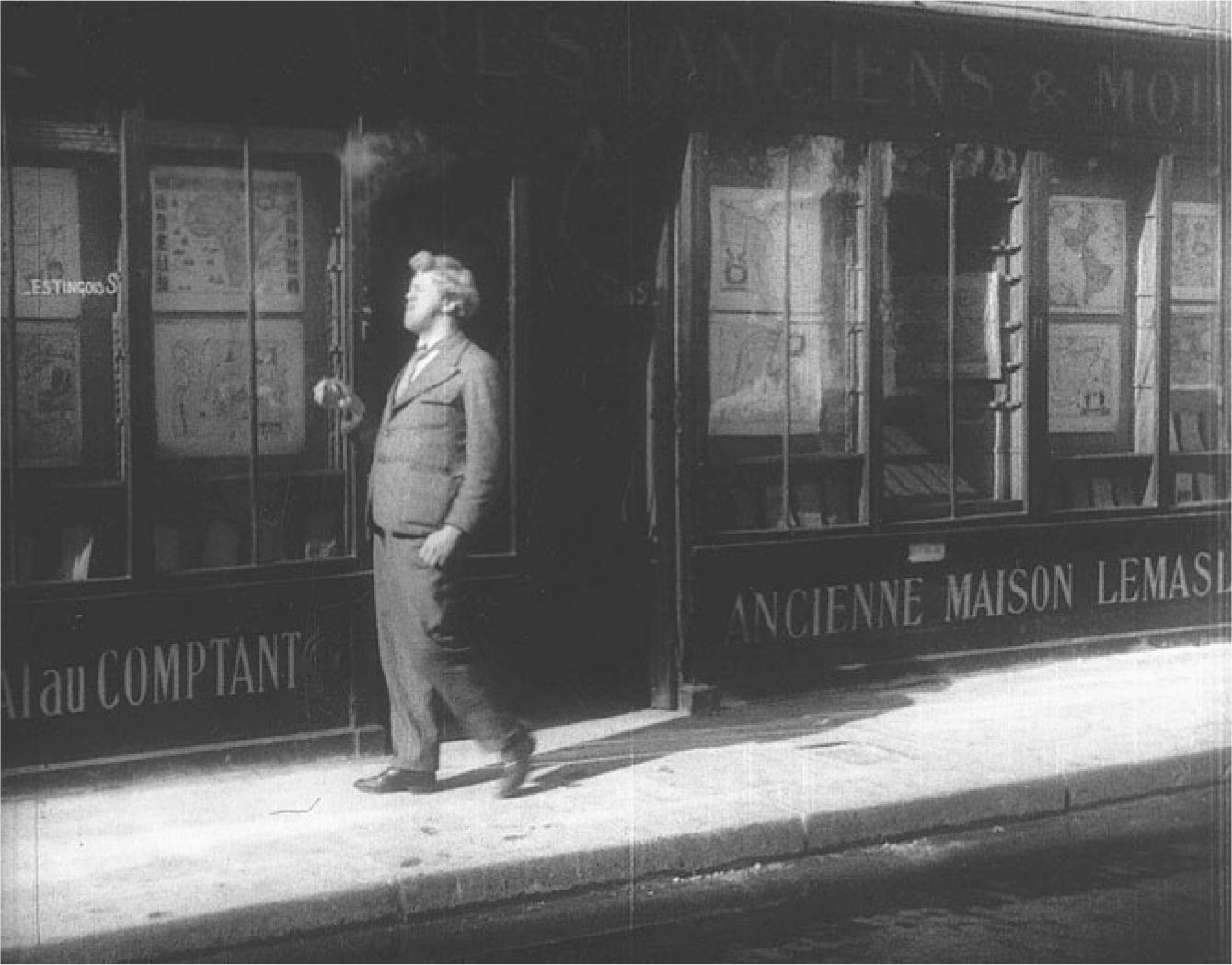 The exhibit showcases a scene from the film “Boudu sauvé des eaux” featuring Boudu confidently walking in front of the Lestingois Bookstore where the windows display ten classical maps.