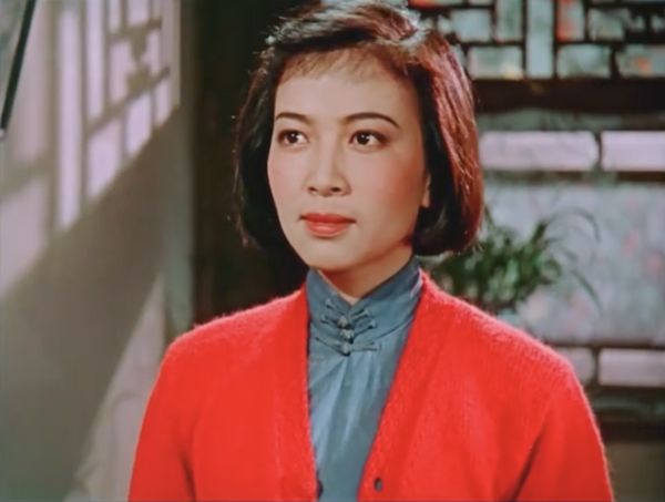 Color still of a young woman in brightly colored orange sweater.