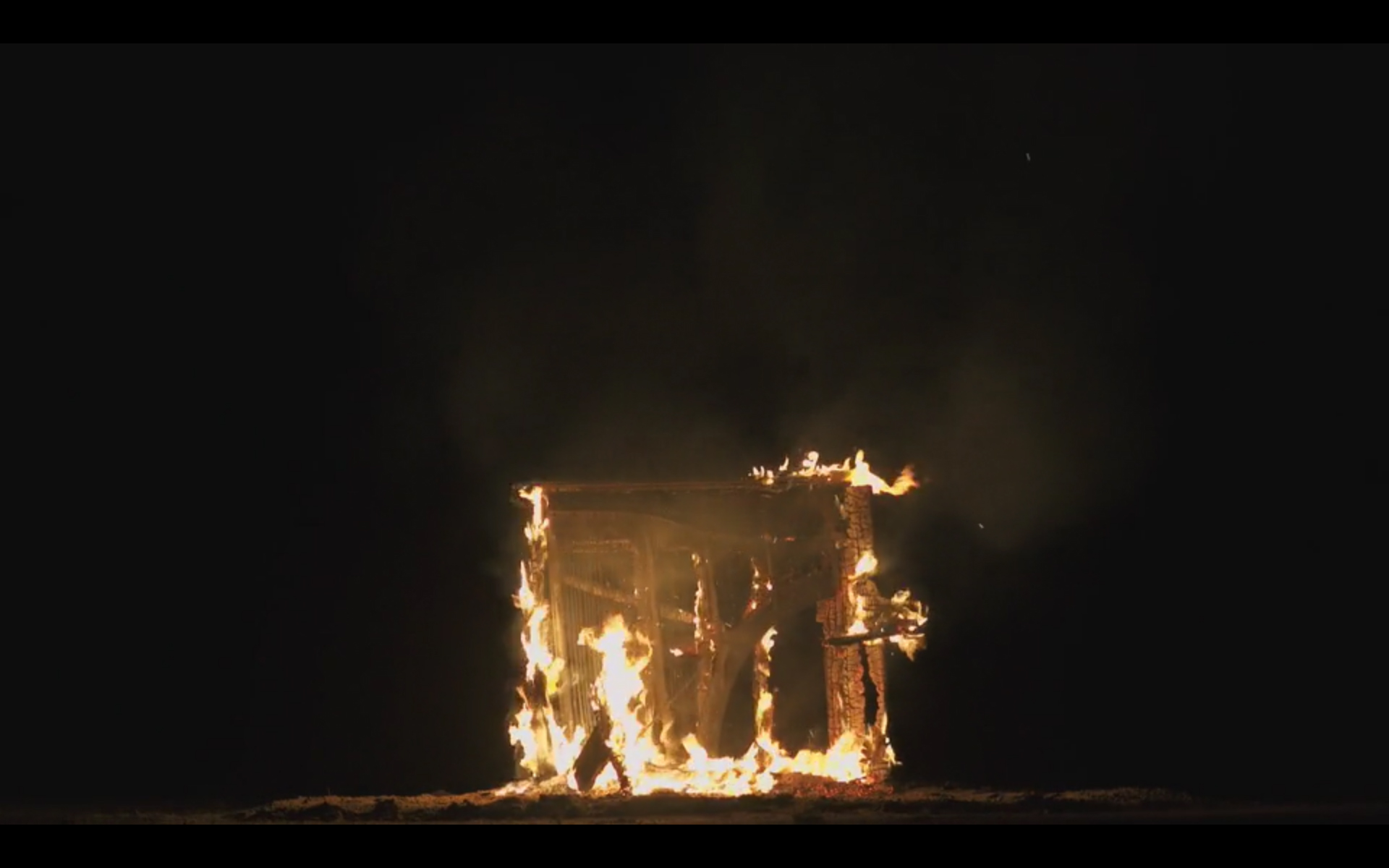 The inner harp of a piano exposed as fire burns through the wooden frame.