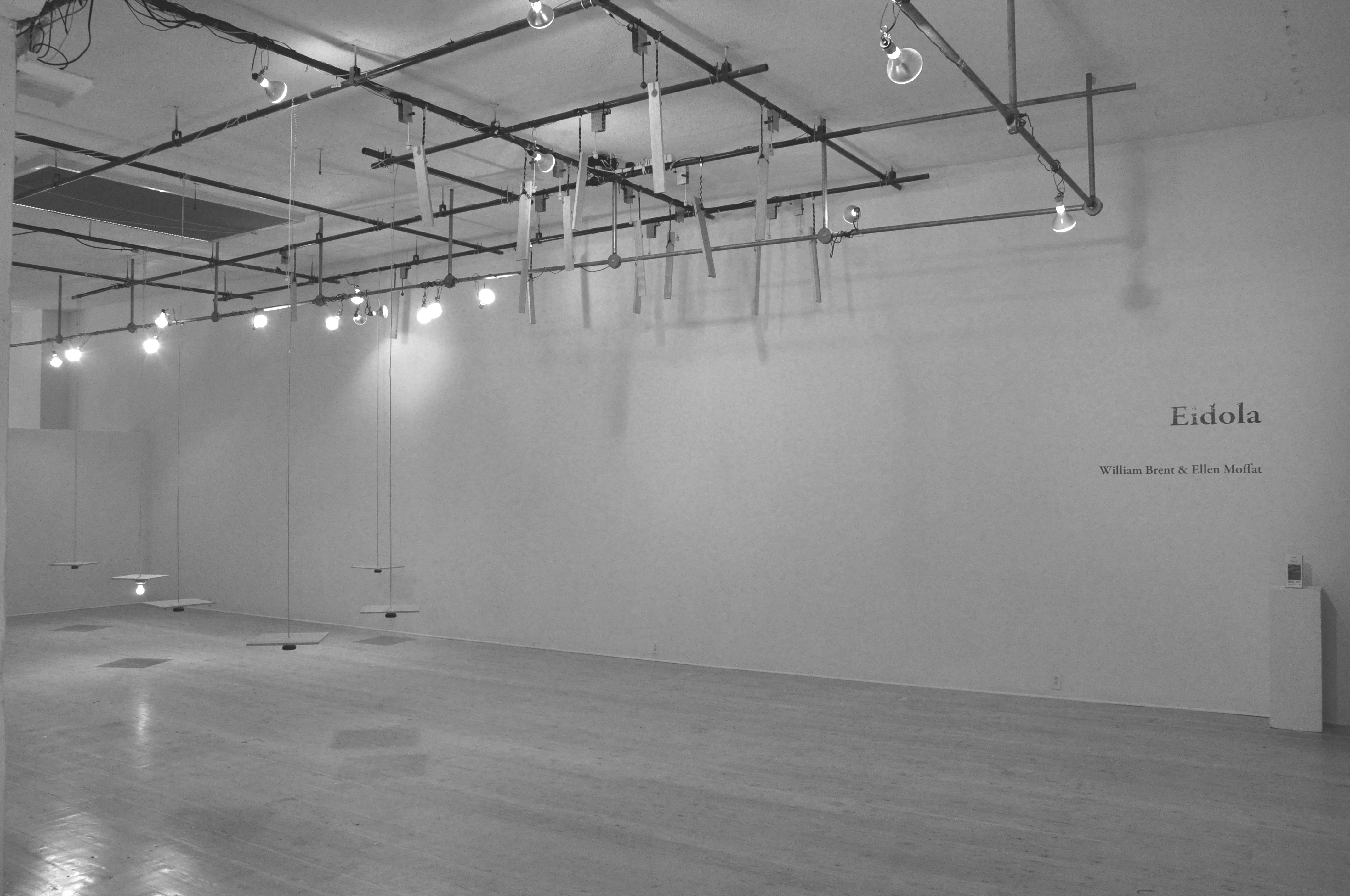 Installation image of Eidola showing both the suspended panels of Basement Suite and False Ruminations mounted to the lighting grid in the ceiling.