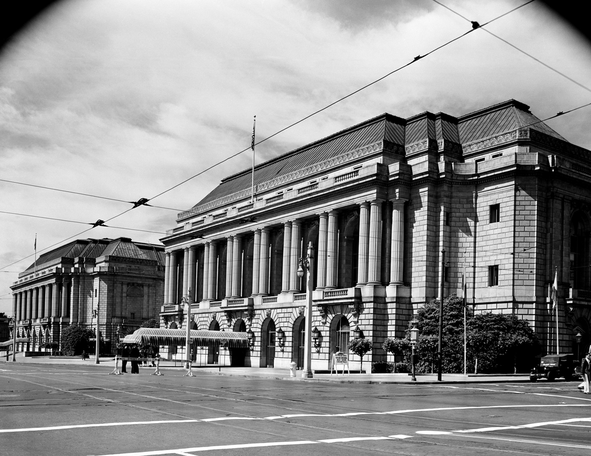 Photograph of the front façades of two almost identical neoclassical buildings facing a main empty avenue.