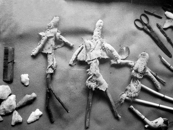 Three seventeenth-century dolls in museum display with other everyday objects.