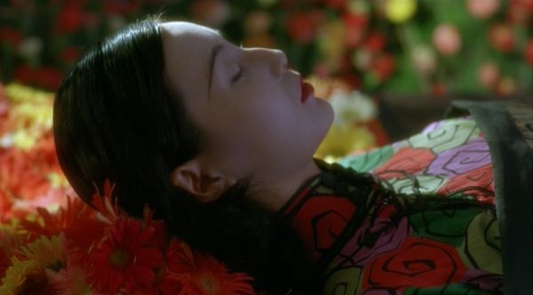 Woman in floral dress lying on a bed of flowers.