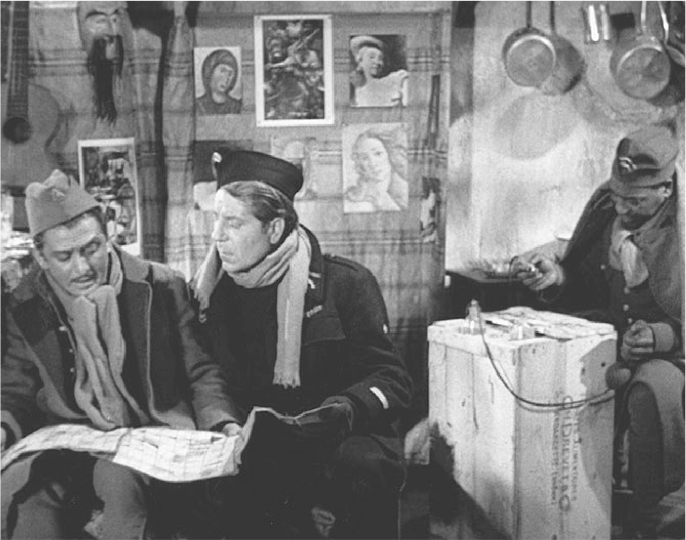 The exhibit showcases a scene from “La Grande Illusion” where three men are in a room, with two of them looking at a map and engaging in conversation while seated in chairs.