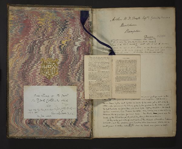 A pamplhet opened to a spread, attached by ribbon to the interior cover of a larger text.