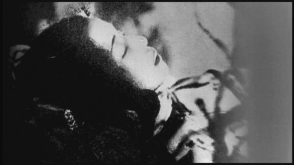 Historical black and white photo of a woman’s corpse lying in repose.
