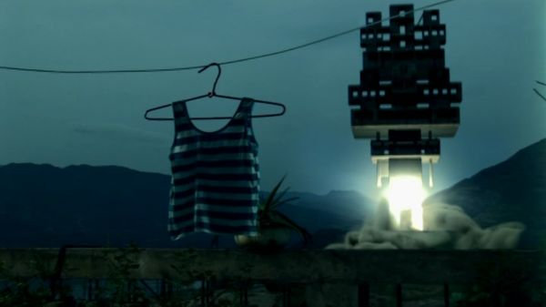 A building blasting off into orbit in the background; in the the foreground a shirt on a clothesline.