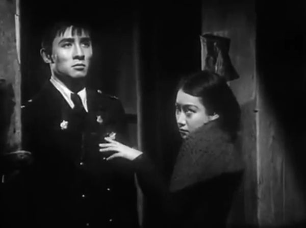 Shadowy image of a woman in a fur-lined coat putting her hand on the chest of a police officer standing near her.