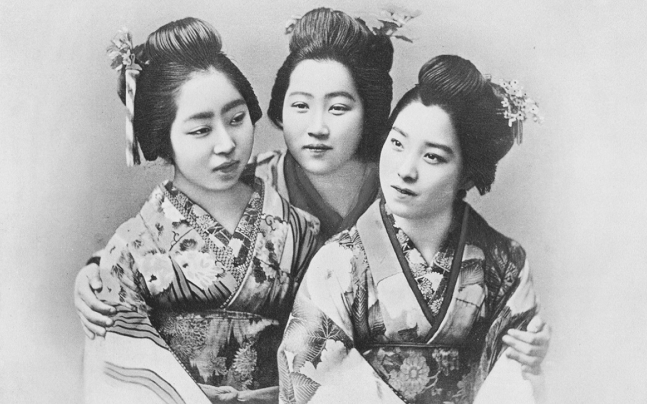 A comic diagram of three women in traditional attire, hair tied up with flowers and bands standing together besides each other with the woman in the middle holding the others by their shoulders.