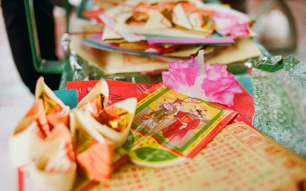 A close up of a table covered with an array of Joss Paper, some sheets folded into flower shapes, others laying flat.
