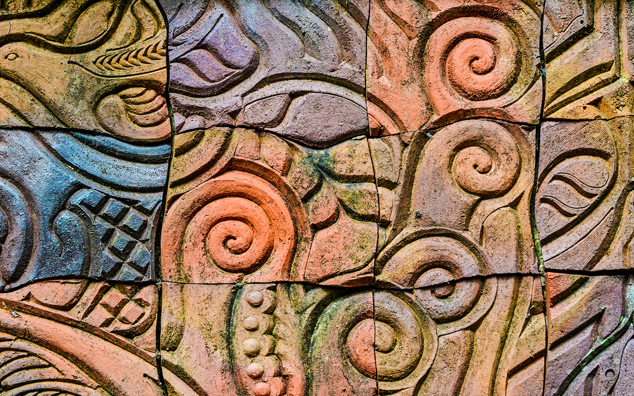 Spiral carvings in brown, red, and blue concrete bricks 