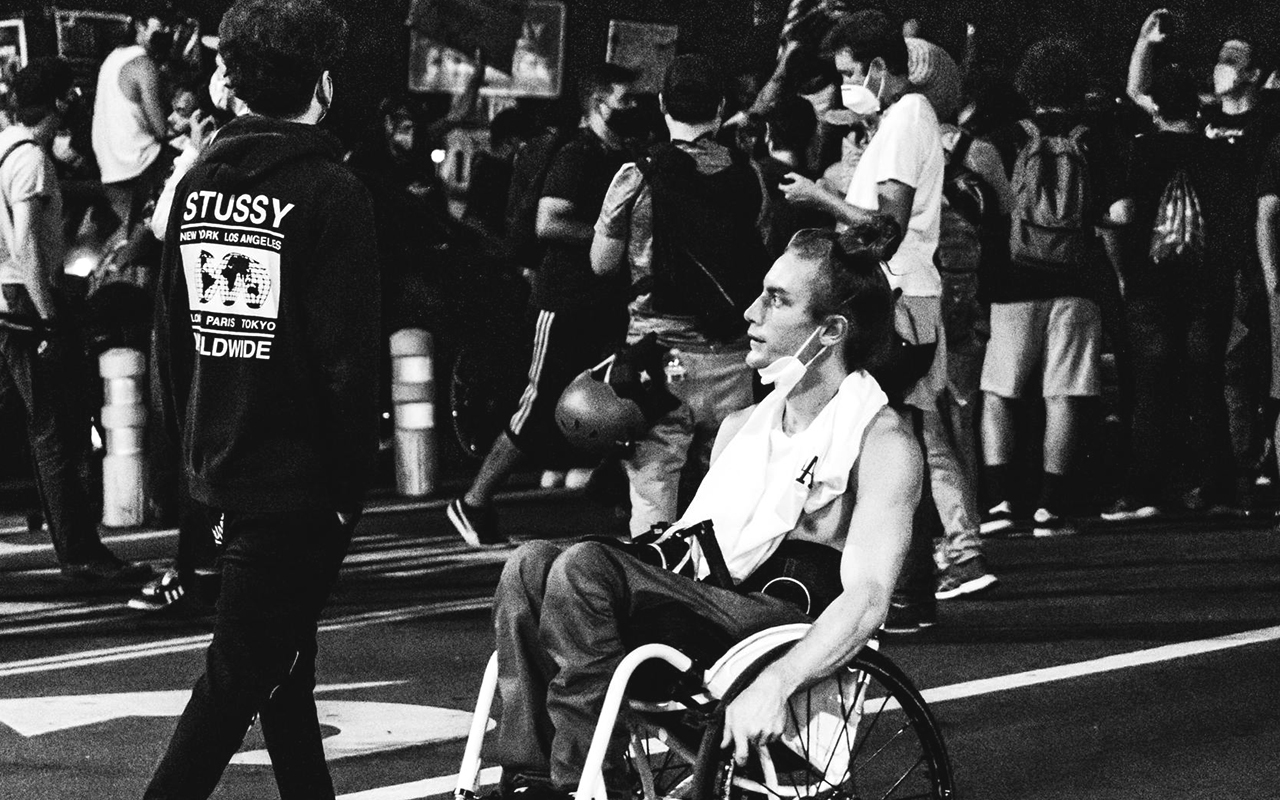 Man in a wheelchair participating in a protest in the street.