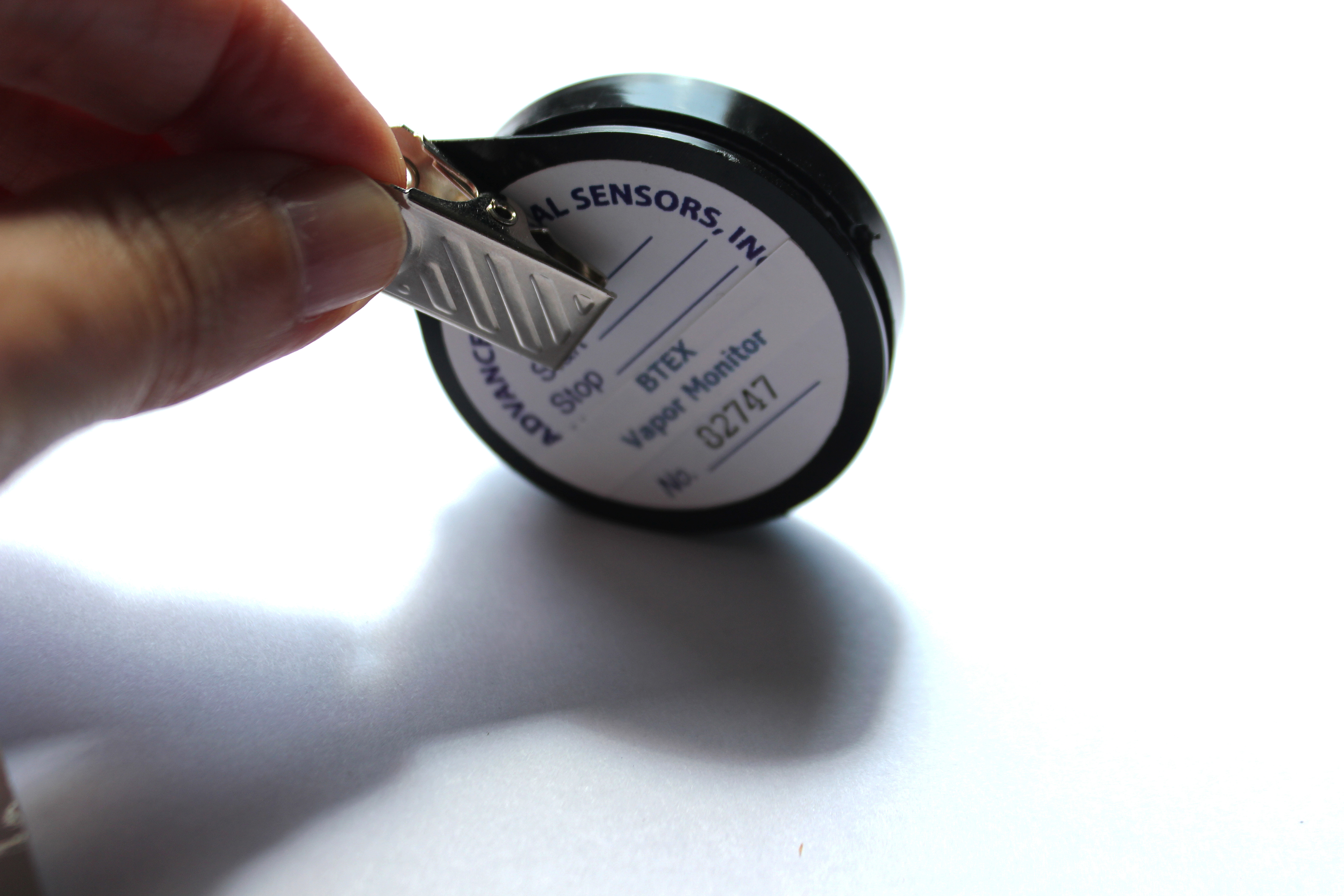 Button-sized circular sensor enclosed in black casing attached to a badge clip.