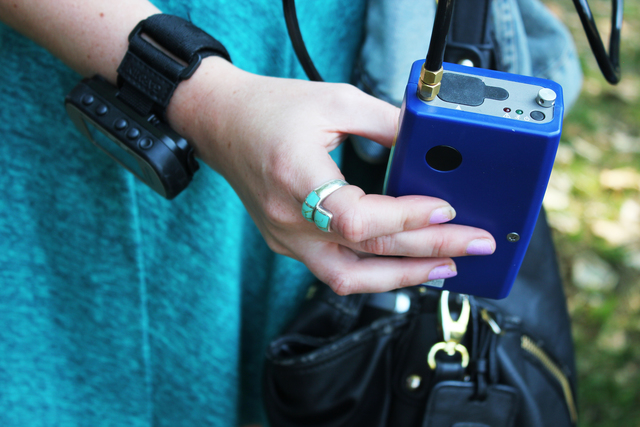 A calculator-sized sensor in blue casing attached to a black cable held in one hand.