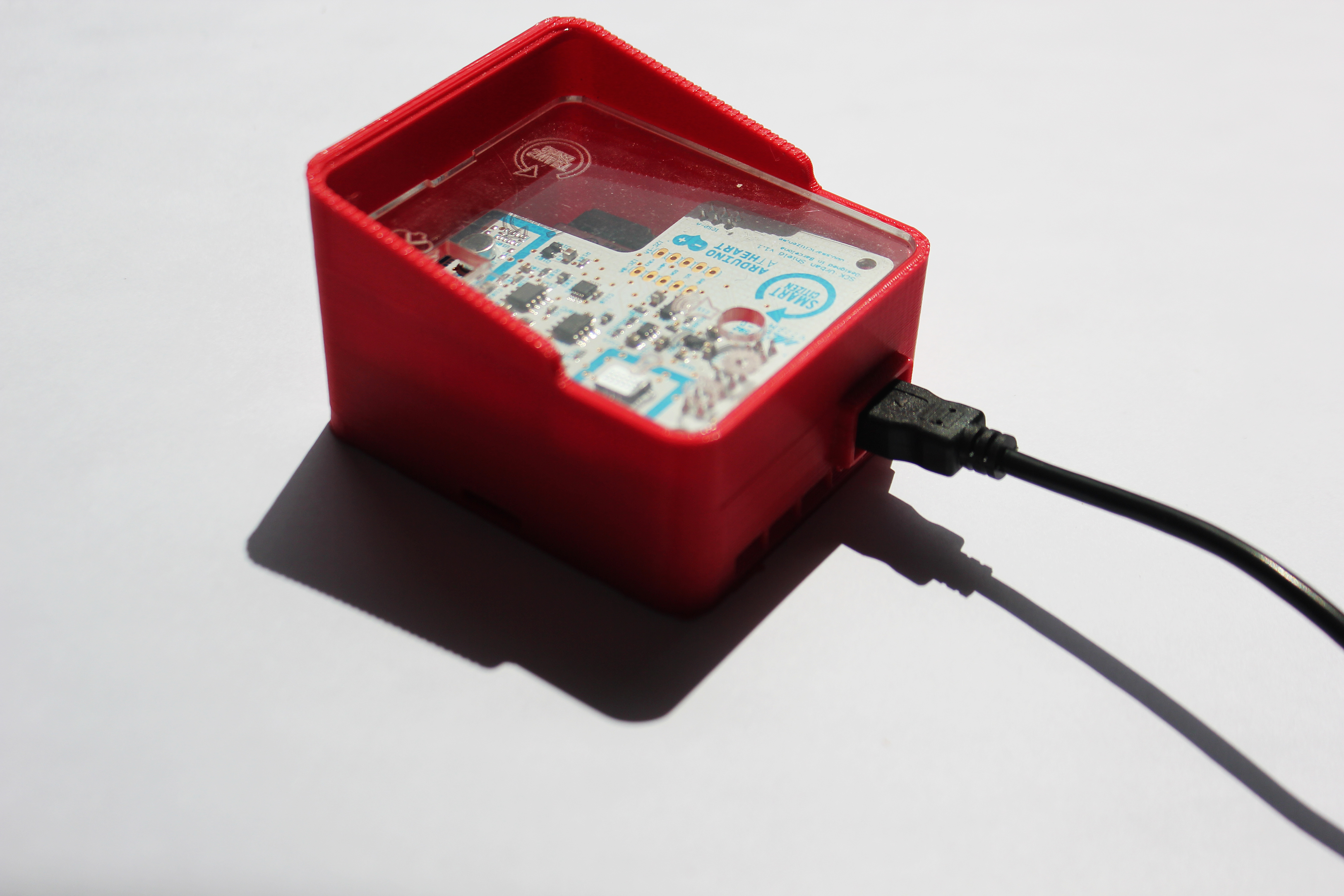Small red casing with transparent top attached to a black cable. A circuit board is visible within.