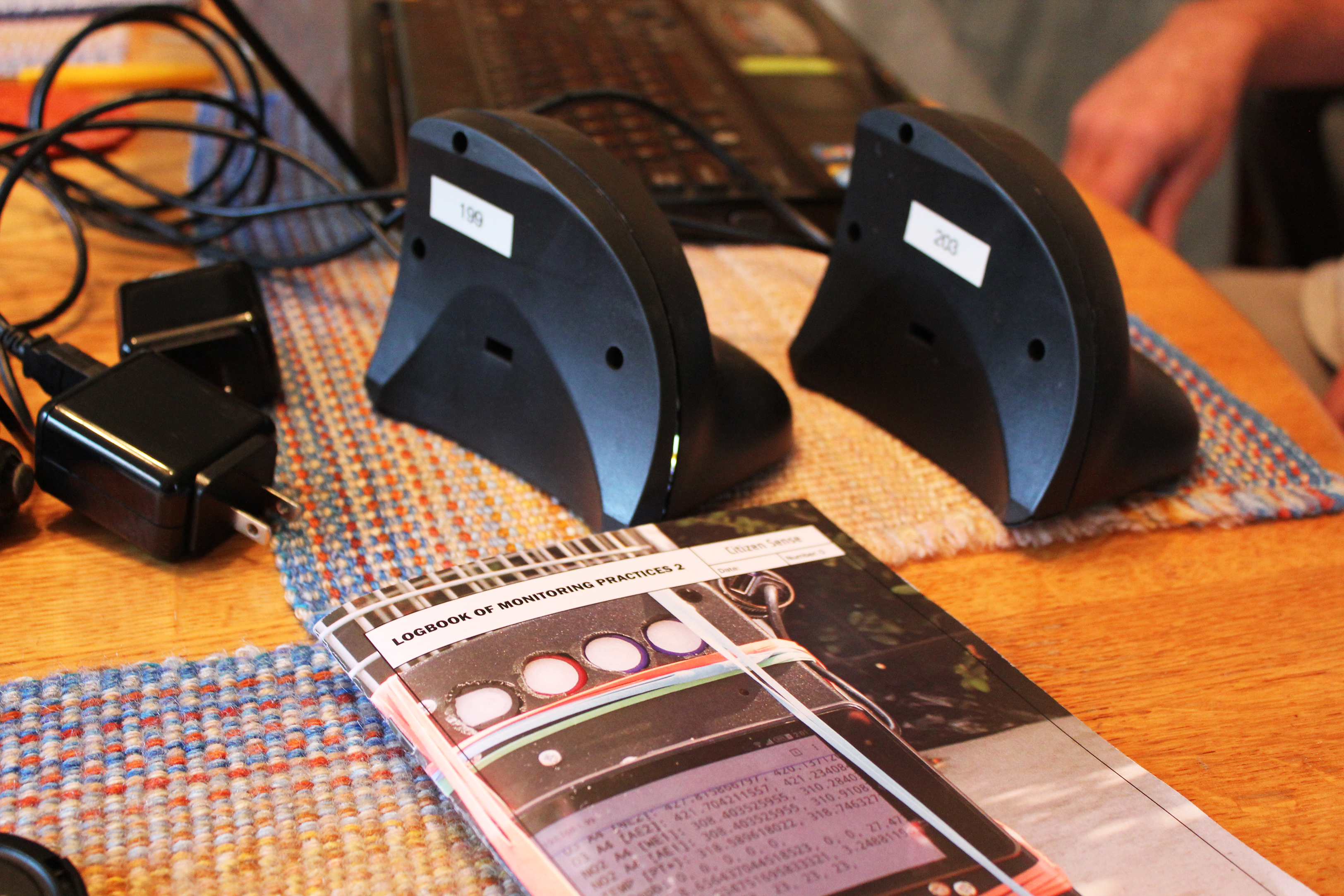 A Citizen Sense pamphlet sits on a table beside wires, plugs, and two small monitor units in black casings.