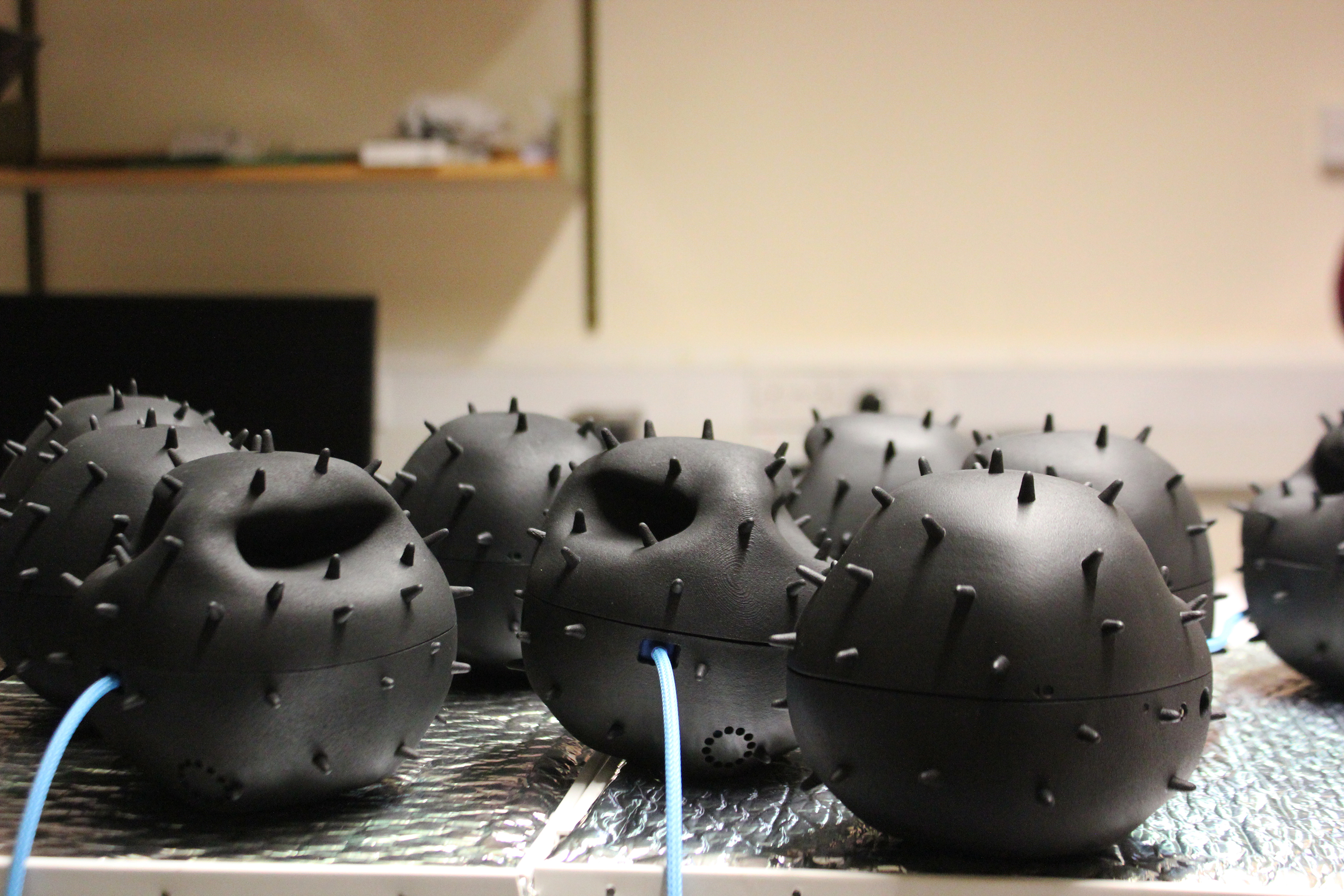 A handful of small, black spherical sensors with small spiky protrusions on a desk.